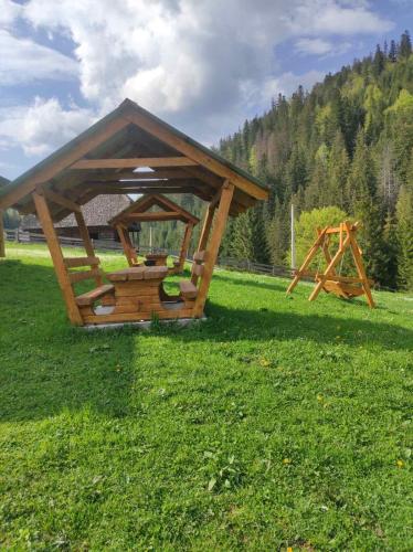 a wooden gazebo in the middle of a field at Шепіт Карпат in Synevyrsʼka Polyana