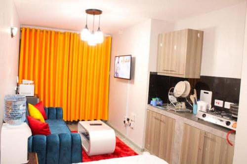 ein Wohnzimmer mit einem blauen Stuhl und einem orangefarbenen Vorhang in der Unterkunft Lux Suites Tsavo Studios Embakasi in Nairobi