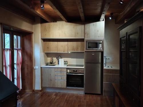 una cocina con electrodomésticos de acero inoxidable y armarios de madera en Esquí, Aigüestortes y Boí-Taüll a tus pies en EbreHogar, en Pla de l'Ermita