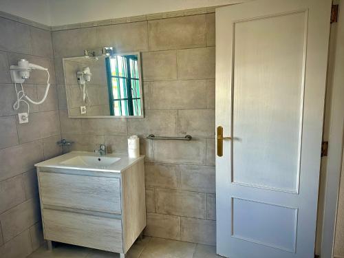 a bathroom with a sink and a mirror and a door at Bungalows Doble UVE in Tías