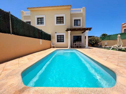 a swimming pool in front of a house at FTV Holidays Homes in Corralejo