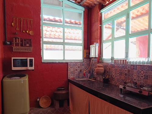 a kitchen with red walls and a sink and windows at Sulu's Nature Farm in Lonavala