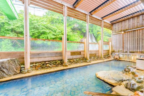 a swimming pool in a house with a large window at Ooedo Onsen Monogatari Hotel New Shiobara in Nasushiobara