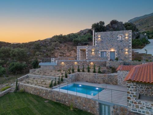 a villa with a swimming pool on a hill at Nature Villas Myrthios in Plakias