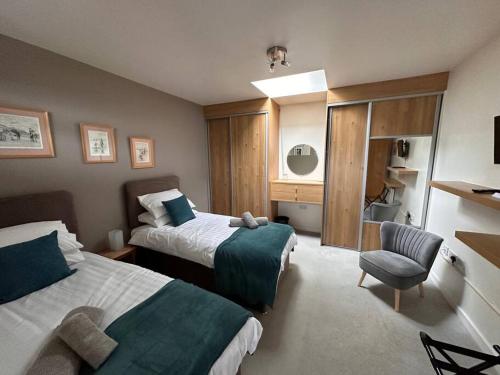 una habitación de hotel con 2 camas y una silla en Ridge House Stables, en Ashford
