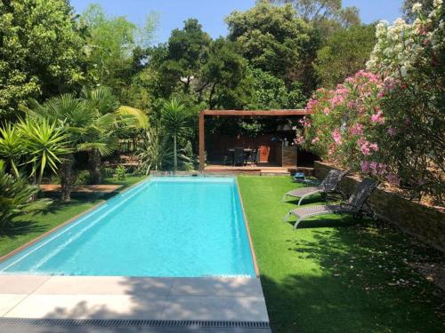 - une piscine dans une cour agrémentée de chaises et de fleurs dans l'établissement L' Arbouseraie, à Saint-Raphaël