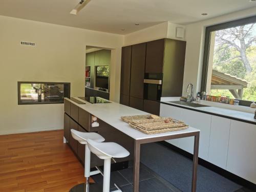 une cuisine avec une table et deux tabourets blancs dans l'établissement L' Arbouseraie, à Saint-Raphaël