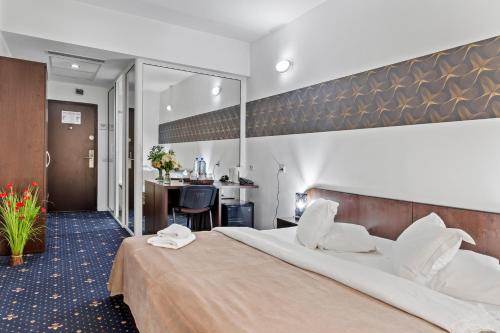 オトペニにあるHotel Charter Otopeniの大きなベッドとデスクが備わるホテルルームです。
