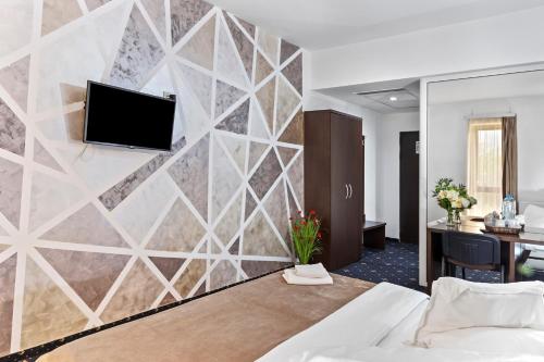 ein Wandbild in einem Hotelzimmer mit einem TV in der Unterkunft Hotel Charter Otopeni in Otopeni