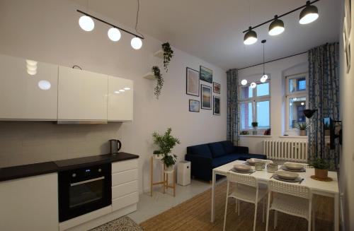 een keuken en een woonkamer met een tafel en een blauwe bank bij Plac Ratuszowy 50 - Old Town in Jelenia Góra