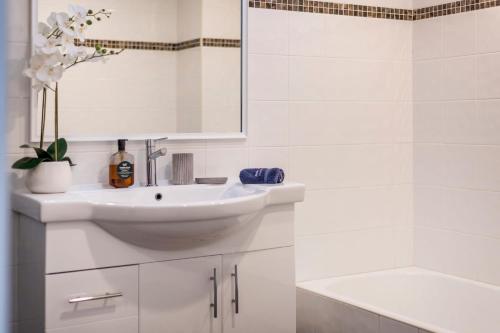 a white bathroom with a sink and a tub at La Ronde Three - Unit 3 - Oceanstays in Yamba