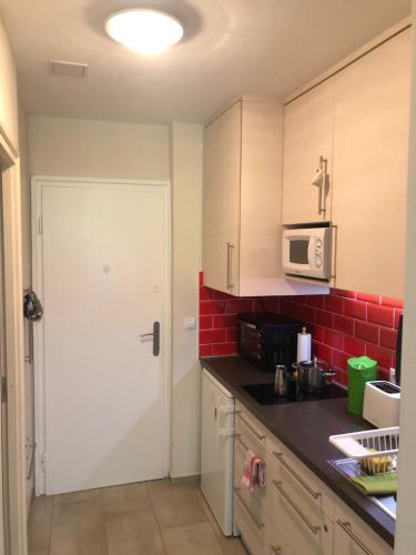 uma cozinha com uma porta branca e azulejos vermelhos em Csopak Apartman em Csopak