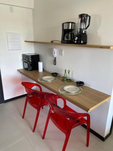 a table with two red chairs in a kitchen at Lar aconchegante Praia do Forte in Praia do Forte