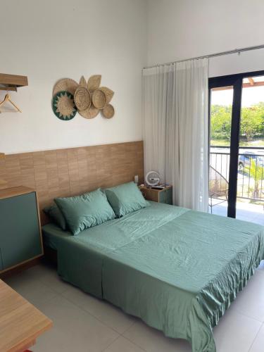 um quarto com uma grande cama verde e uma varanda em Lar aconchegante Praia do Forte na Praia do Forte
