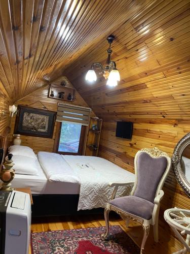 1 dormitorio con 1 cama y 1 silla en una cabaña en İSGOBYA DAŞ GONAK DAĞ EVLERİ, en Trabzon