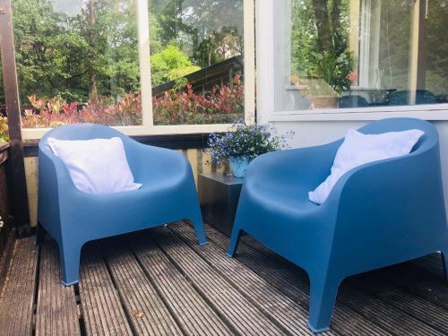 two blue chairs sitting on a porch next to a window at Tiny house 't Heidehoes in Usselo in Enschede