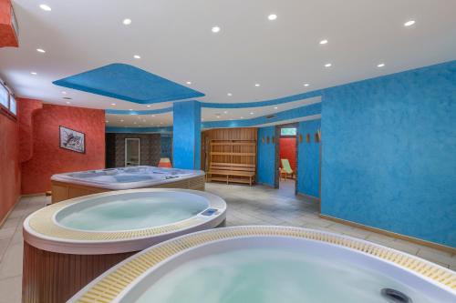a large bathroom with two tubs and a blue wall at Villa Zina Family Resort in Custonaci