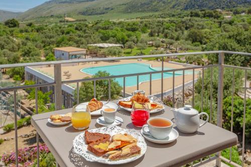 a table with breakfast foods and coffee and a view of a pool at Villa Zina Family Resort in Custonaci