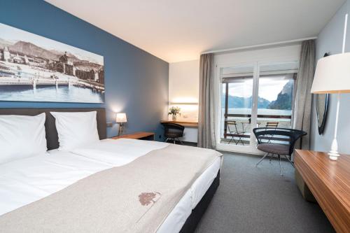 um quarto de hotel com uma cama, uma secretária e uma janela em Seehotel Kastanienbaum em Lucerna