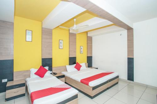 2 łóżka w pokoju z żółtymi ścianami i czerwonymi poduszkami w obiekcie OYO 8501 ABHIMAANI COMFORTS w mieście Bengaluru