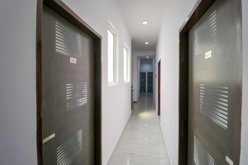 un pasillo con dos puertas marrones y un pasillo con un pasillo con un pasillo en OYO 71370 White House, en Garhi Harsāru