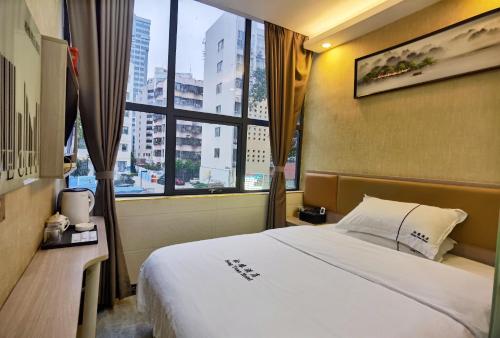 a hotel room with a bed and a large window at Songyuan Hotel 松缘酒店 in Shenzhen