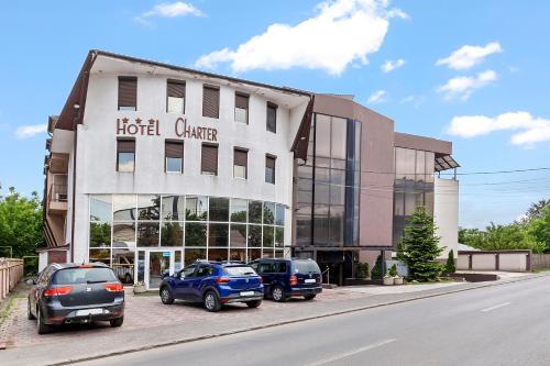 a hotel with cars parked in front of a building at Hotel Charter Otopeni in Otopeni
