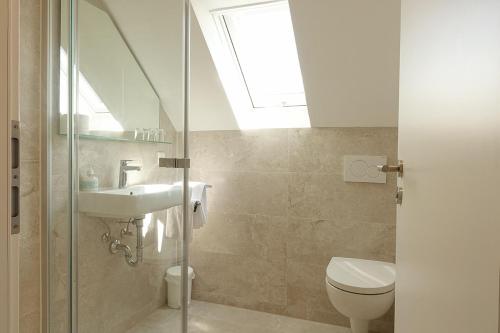 łazienka z toaletą, umywalką i oknem dachowym w obiekcie Gästehaus Hornstein w mieście Nonnenhorn