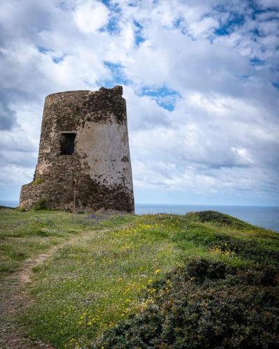 an old stone building on a grassy hill next to the ocean at La casa di Mo' in Torre Dei Corsari