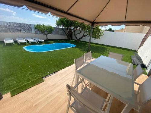 um pátio com uma mesa e cadeiras e uma piscina em vistalmar 1 casa verde em San Juan de Alicante