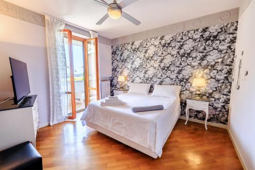 um quarto com uma cama branca e uma televisão em B&B Il Tiglio em Porto SantʼElpidio