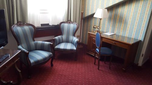 Habitación de hotel con 2 sillas, escritorio y escritorio. en Hotel Biasutti, en Lido de Venecia