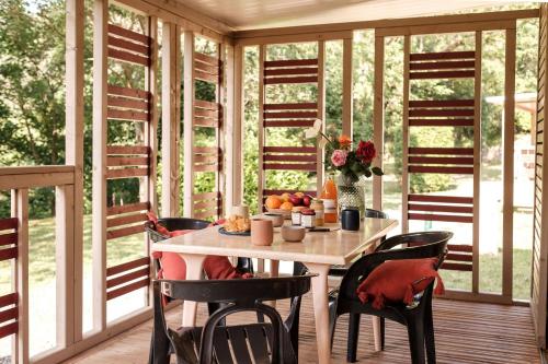 a room with a table and chairs on a porch at INSPIRE Villages - Anduze in Corbés