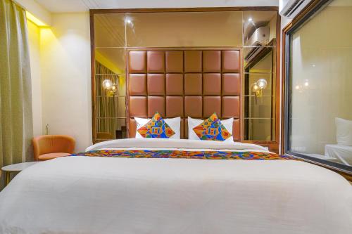 a bedroom with a large bed with a large headboard at FabHotel Benchmark in Indore