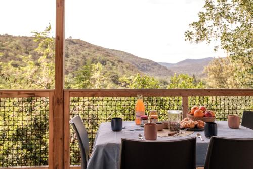 a table with a bowl of fruit sitting on a balcony at Slow Village Anduze - Cévennes in Corbés
