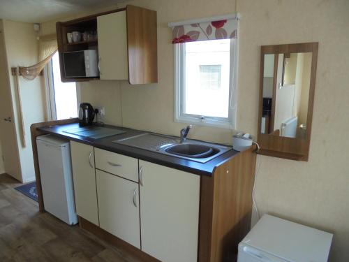 a small kitchen with a sink and a window at Highfield and Haven : Elegance:- 4 Berth Central Heated in Lincolnshire