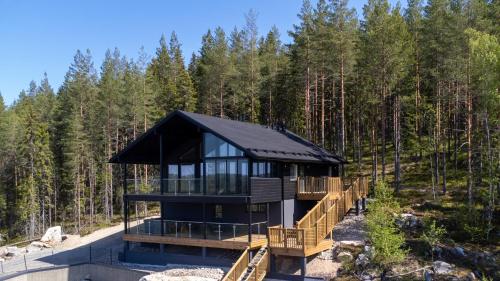 uma casa na floresta com um telhado preto em Luksushuvila Himos Panorama em Jämsä
