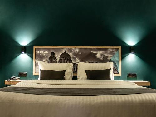 1 dormitorio con 1 cama grande y una pintura en la pared en LOKAL Rooms x Shahrah-e-Faisal (Nursery) en Karachi