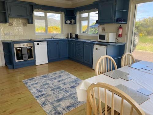 a kitchen with blue cabinets and a table with chairs at Tearmann Solais in Schull