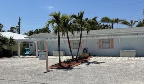 a white house with palm trees in front of it at Manasota Key Cottage B in Englewood