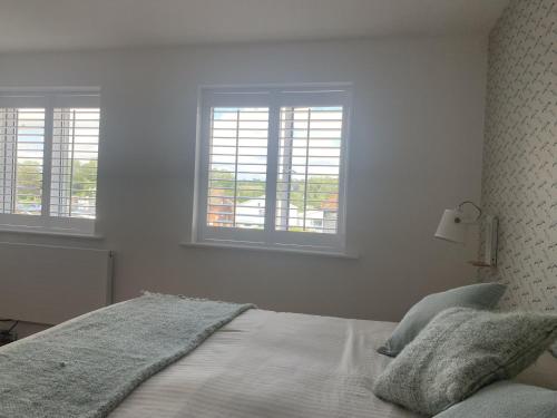 a white bedroom with a bed with two windows at The Regent, Rye in Rye