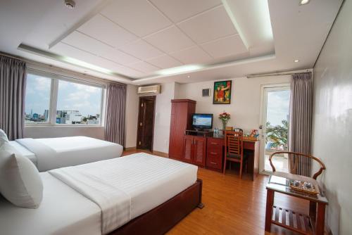 Van Ha Hotel في مدينة هوشي منه: غرفة نوم بسريرين ومكتب فيه تلفزيون