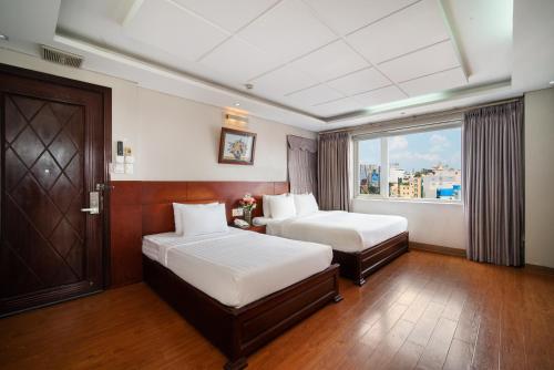 Van Ha Hotel في مدينة هوشي منه: غرفة فندقية بسريرين ونافذة