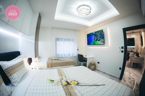 a bedroom with two beds and a tv on the wall at Adria centar Koćuša in Ljubuški