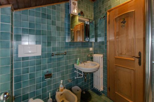 a blue tiled bathroom with a sink and a toilet at Spazioso appartamento centrale con wi-fi in Cortina dʼAmpezzo