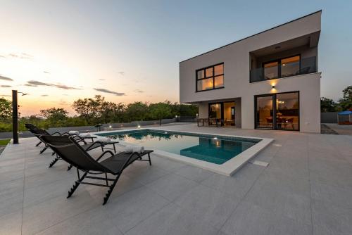 a house with a swimming pool in the backyard at Villa Rocinante ZadarVillas in Murvica