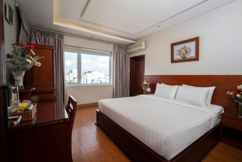 a bedroom with a large white bed and a window at Van Ha Hotel Etown - Nhà Ga T3 Sân Bay TSN in Ho Chi Minh City