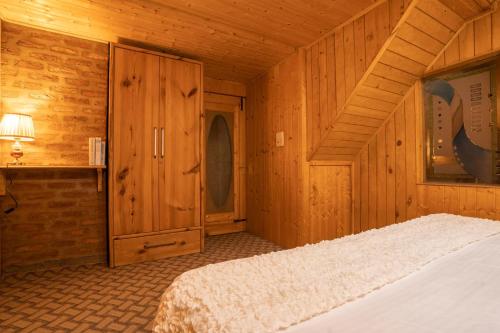 1 dormitorio con 1 cama en una cabaña de madera en StayVista at Lavender Haze - 3BR Cottage, en Pahalgām