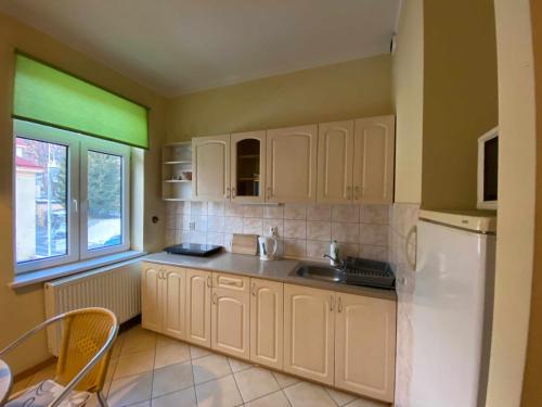 a kitchen with white cabinets and a sink and a window at Apartament w Willi Cis in Krynica Zdrój