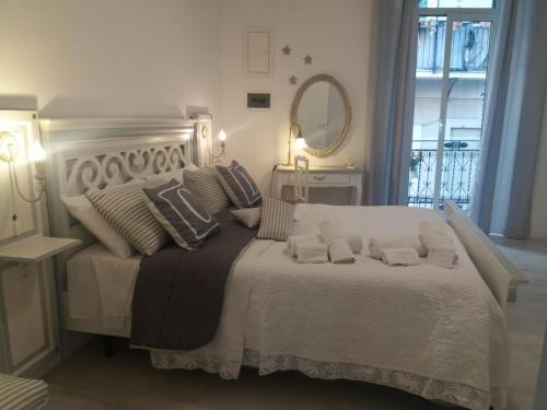 1 dormitorio con cama blanca con almohadas y espejo en Castrum Lodge, en Palermo